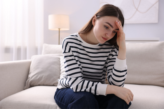 Femme épuisée par la charge mentale dans son couple, assise sur un canapé