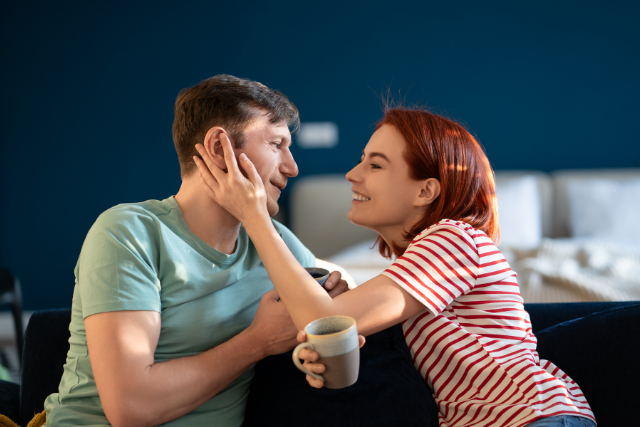 Femme qui caresse le visage de son compagnon, une tasse à la main