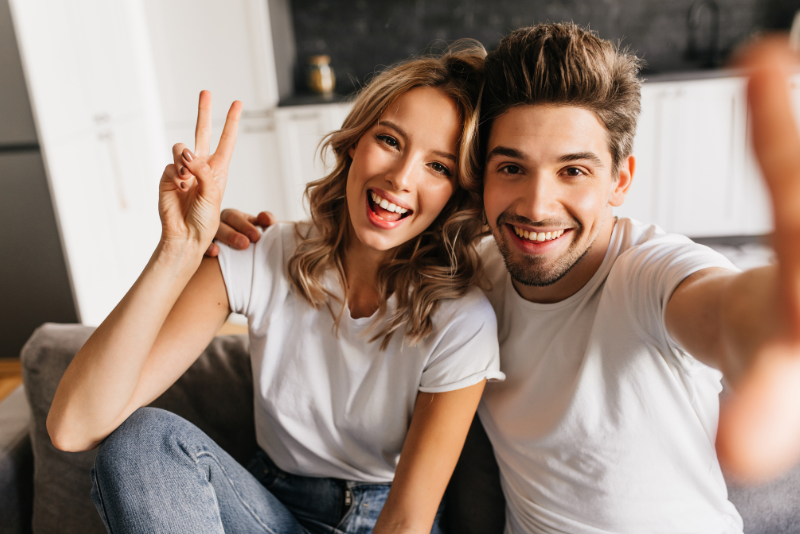 Couple joyeux qui prend un selfie en faisant le signe de la victoire